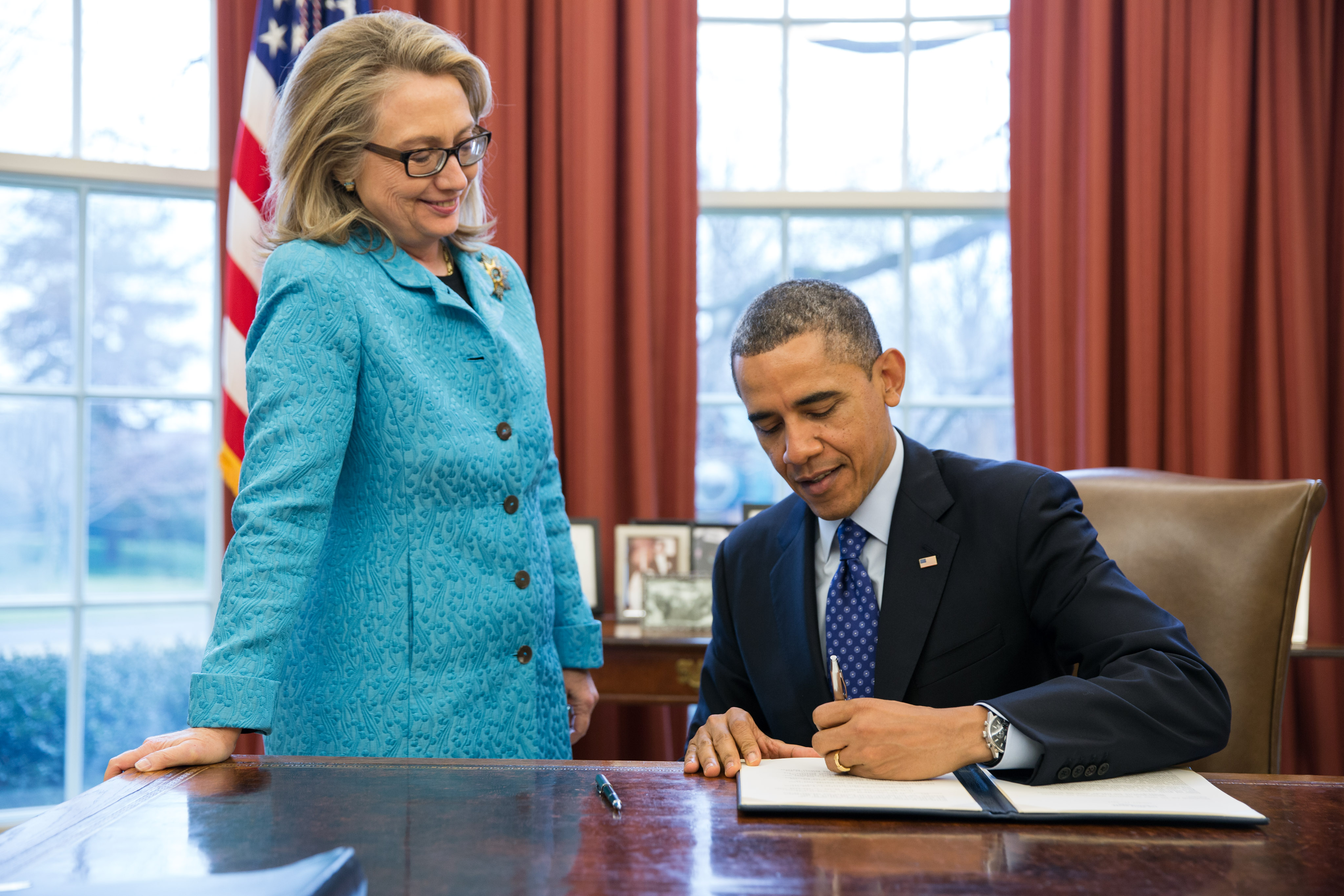 Secretary of State Hillary Clinton watches as President Obama signs a Presidential memorandum (January 20, 2013)
