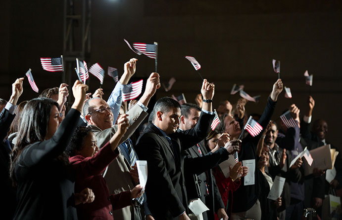 Newly naturalized citizens wave American flags after taking the Oath of Allegiance during a naturalization ceremony at the National Archives in Washington, D.C., Dec. 15, 2015. (Official White House Photo by Pete Souza)