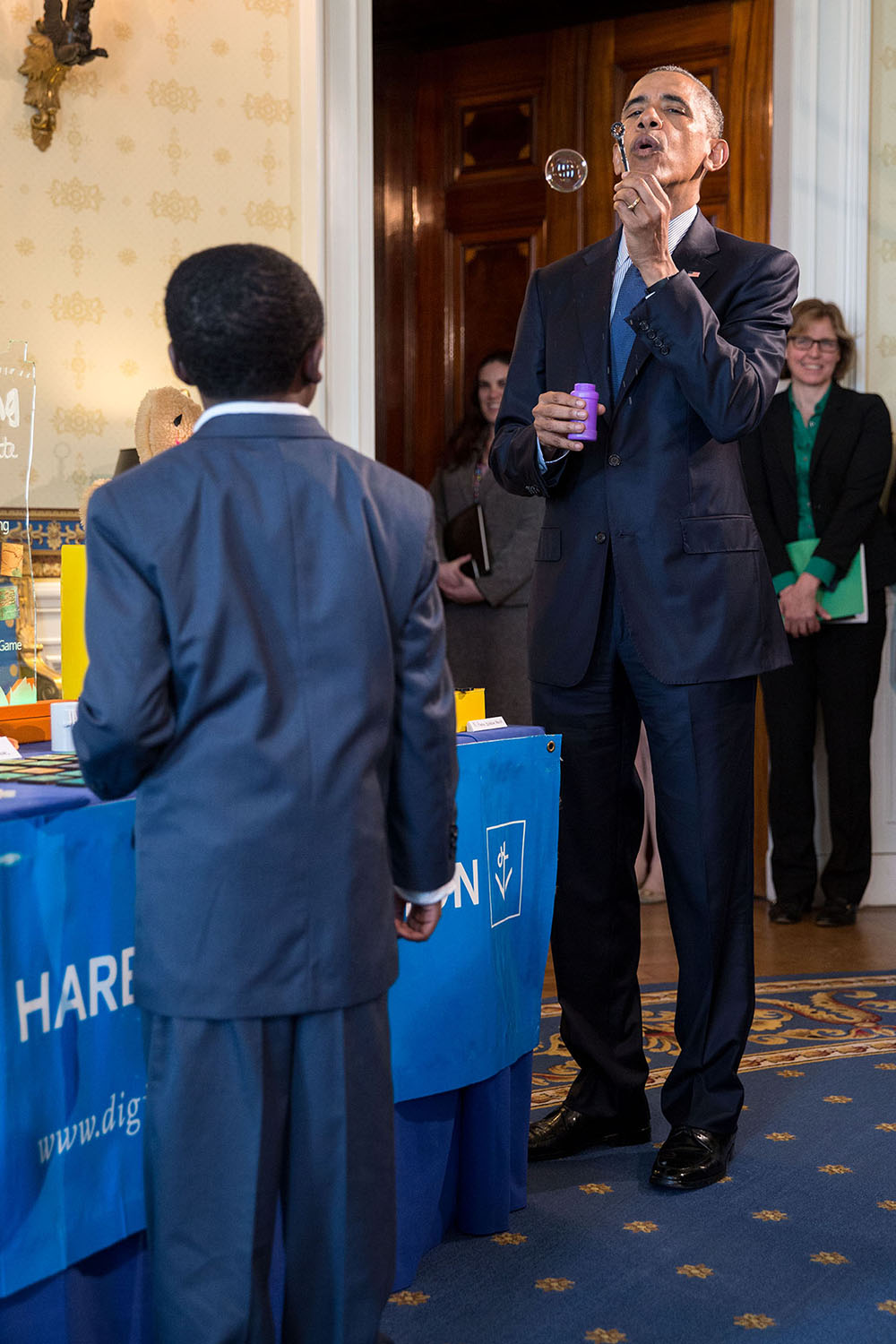 President Barack Obama blows a bubble while talking with nine-year-old Jacob Leggette about his experiments with additive and subtractive manufacturing with a 3D printer, his project that was part of the White House Science Fair in the Blue Room of the White House, April 13, 2016. (Official White House Photo by Pete Souza)