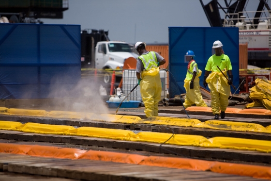 Workers pressure wash inflatable boom at the Theodore Staging Area 