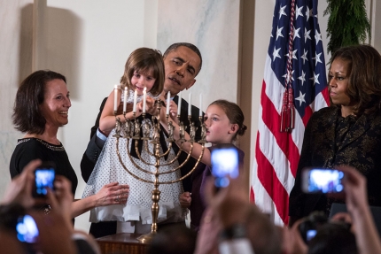 President Barack Obama holds up Kylie Schmitter as she and her sister Lainey Schmitter light the menorah during the Hanukkah reception