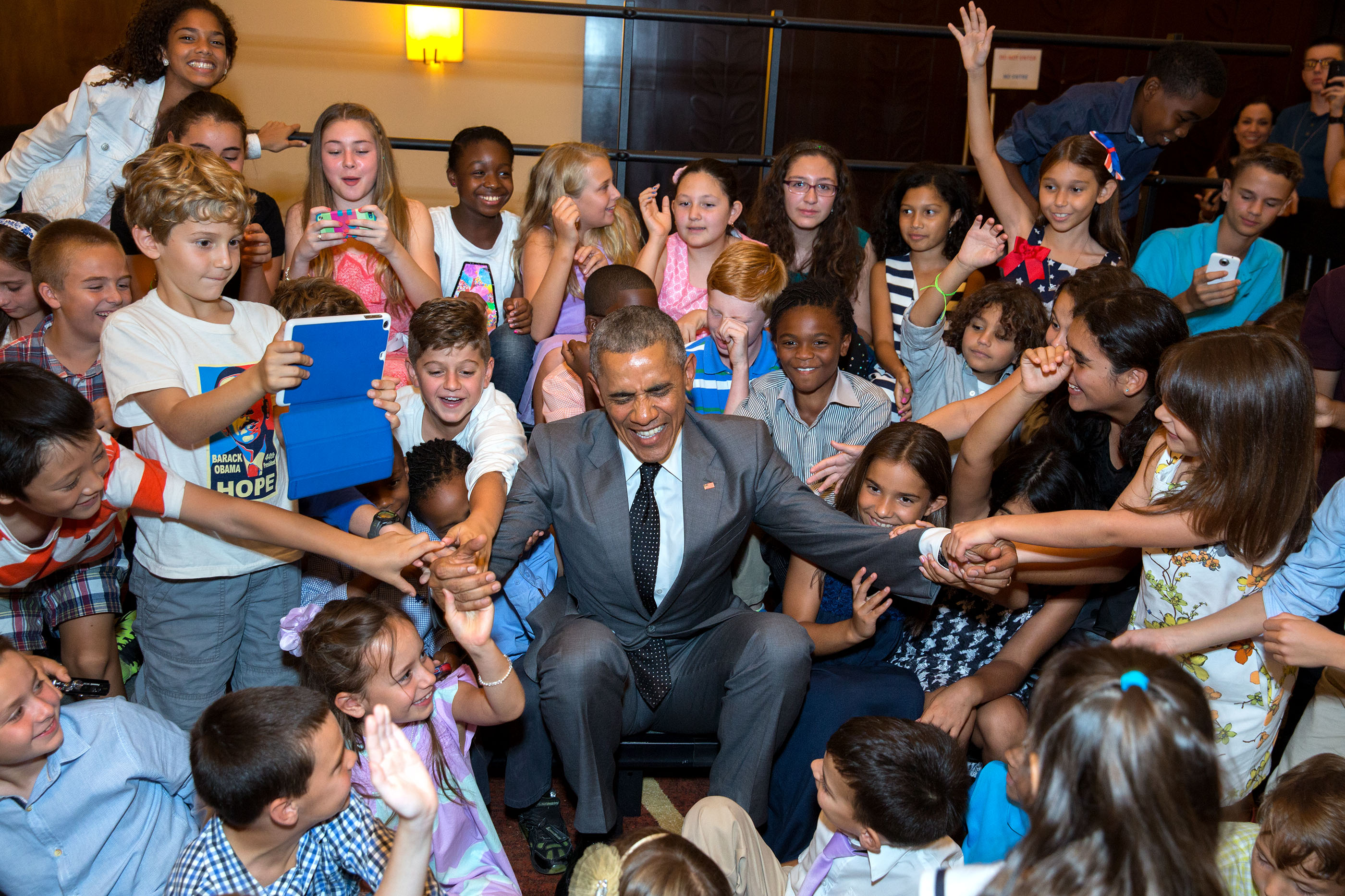 Children of U.S. Embassy personnel help President Obama to his feet after he posed for a group photo with them at the Westin Playa Bonita hotel in Panama City. (Official White House Photo by Pete Souza)