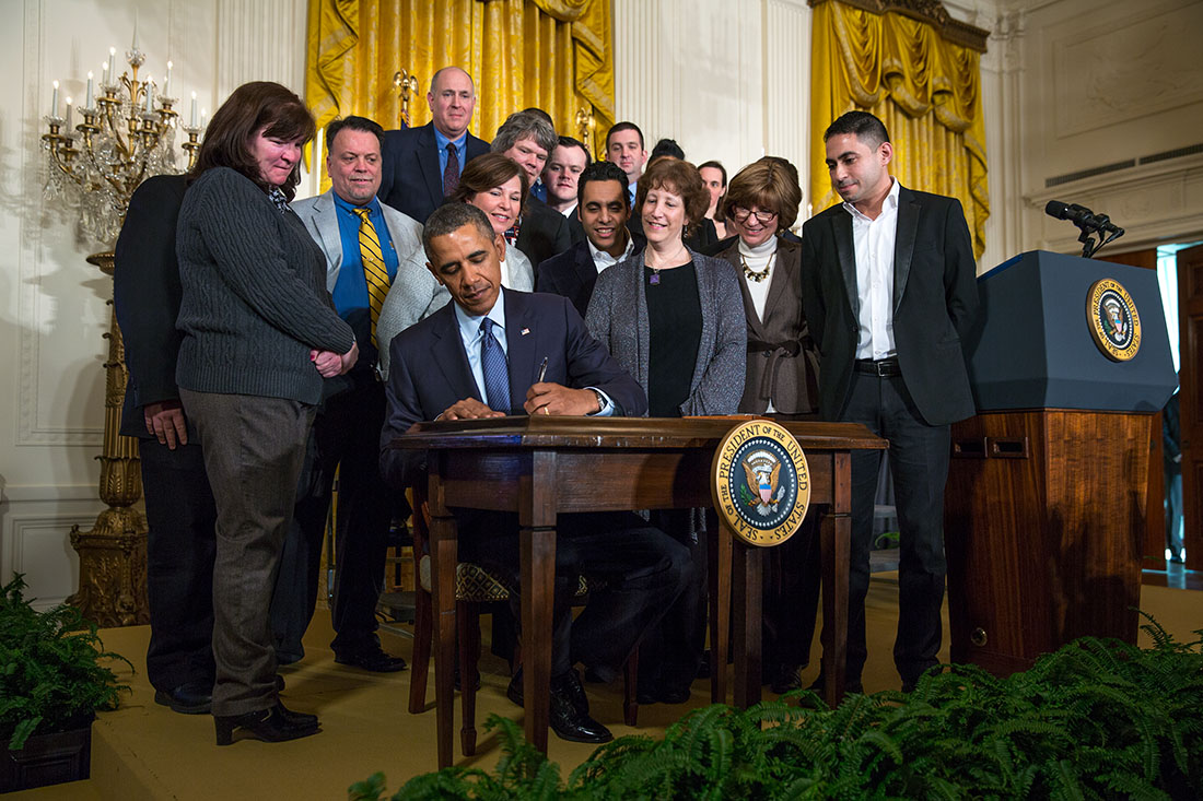 President Barack Obama signs a Presidential Memorandum on updating the overtime pay system, in the East Room of the White House, March 13, 2014.