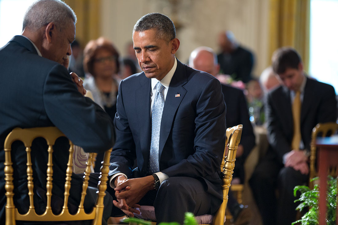 President Barack Obama bows his head as Pastor Joel Hunter gives the opening prayer during the Easter Prayer Breakfast in the East Room of the White House, April 14, 2014.