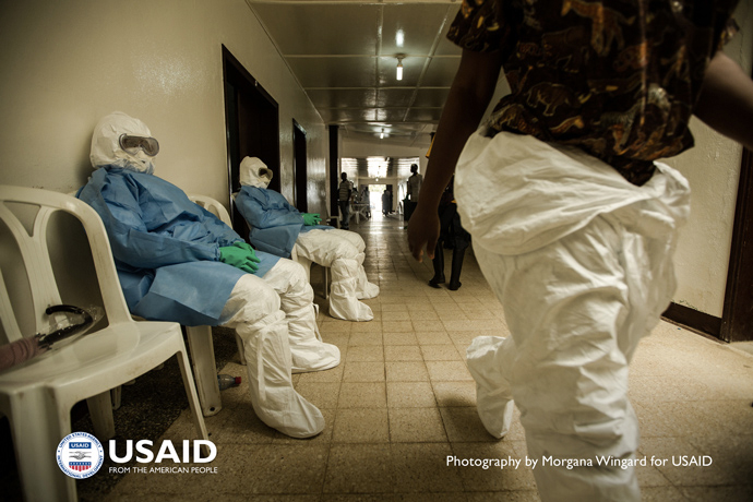 Health workers in personal protective equipment (PPE) wait to enter the hot zone at Island Clinic in Monrovia, Liberia