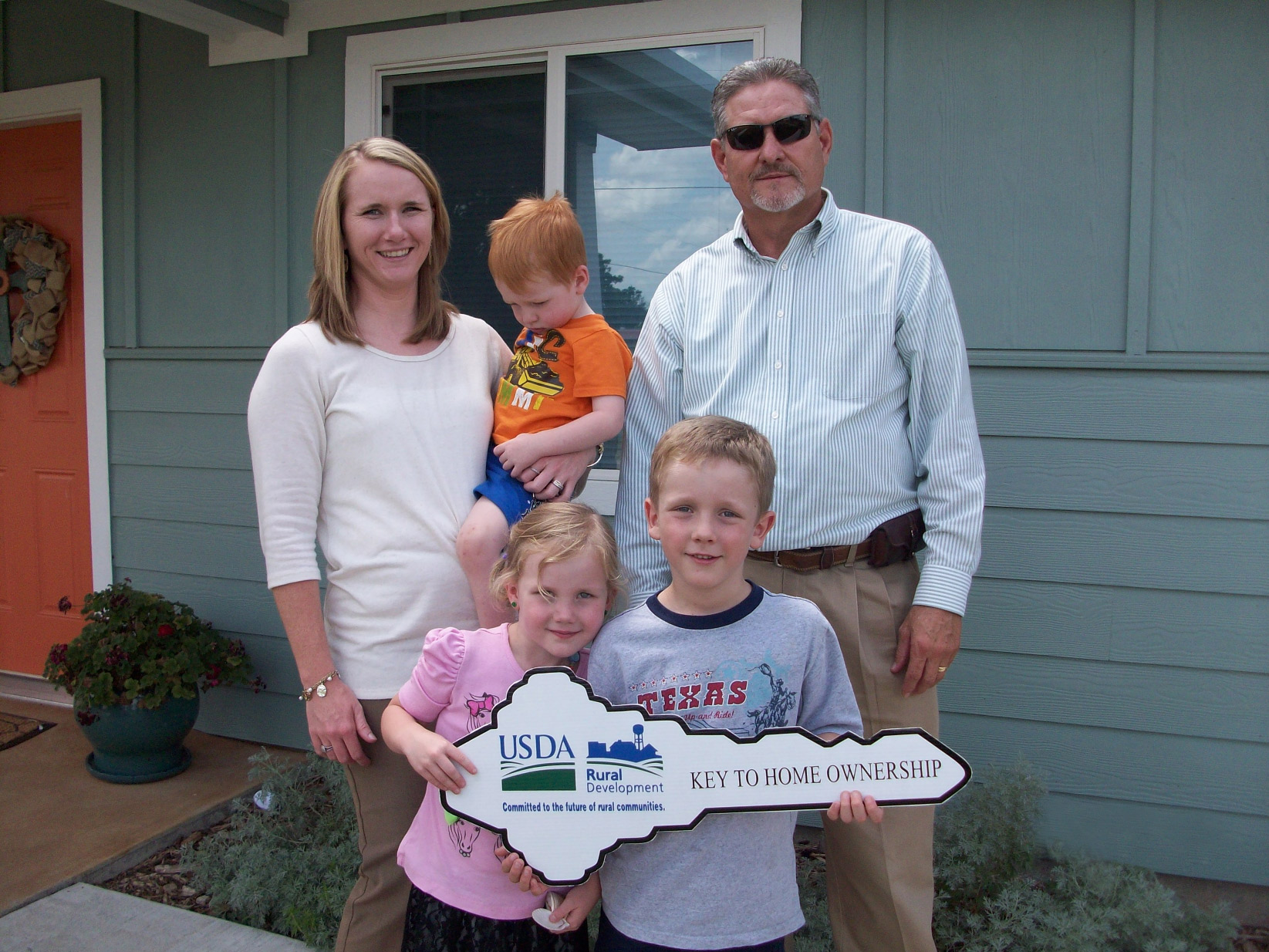 Family stands in front of their new home due to USDA's Rural Development (RD) home ownership program