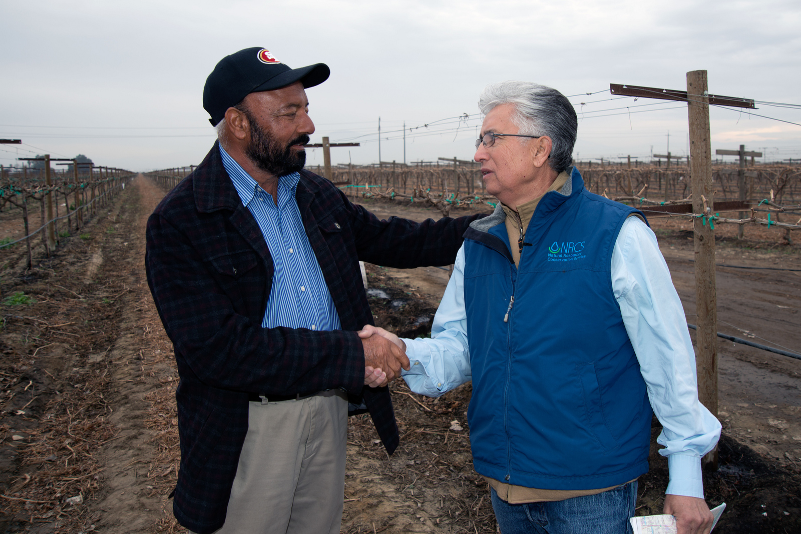 A farmer shakes hands with a USDA Natural Resources Conservation Service (NRCS) employee