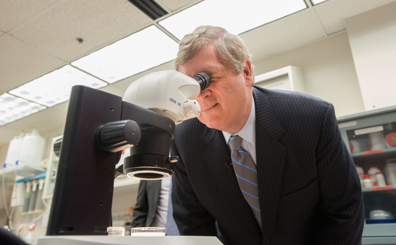 Agriculture Secretary Tom Vilsack looks into a microscope