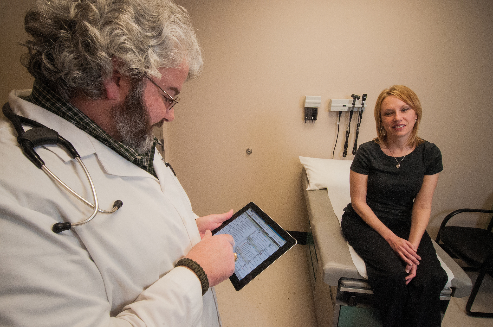 Dr. Albert Warren, MD consults with a patient and records the patient’s symptoms on an electronic tablet