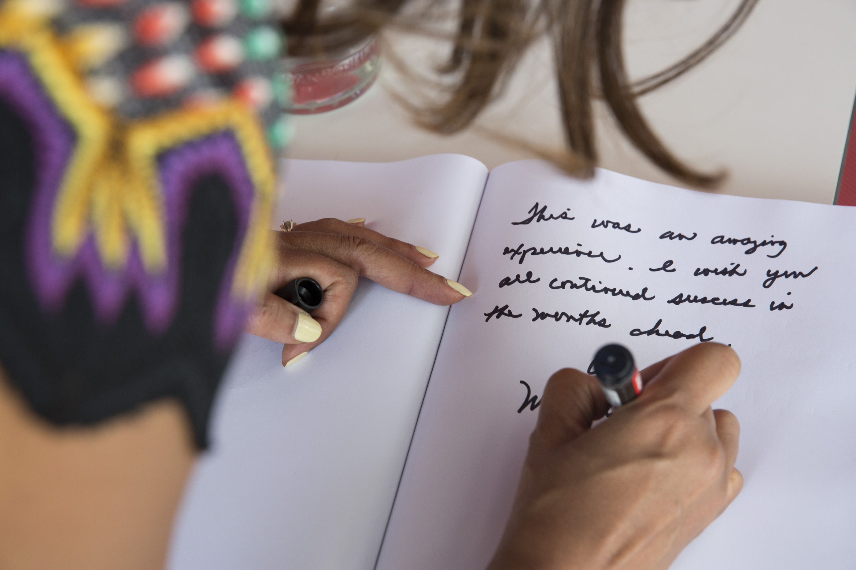 First Lady Michelle Obama signs the guest book in the USA Pavilion