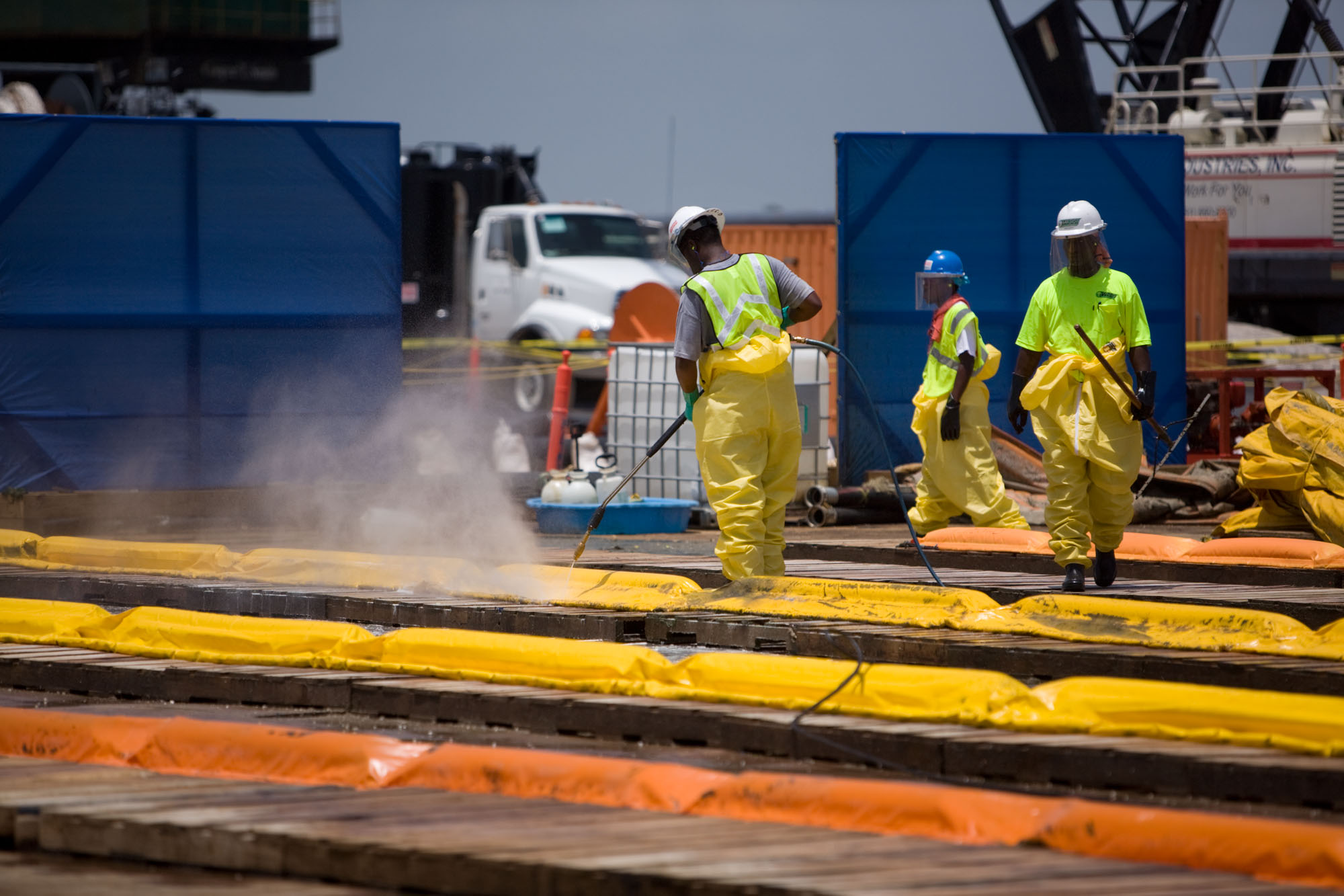 Workers pressure wash inflatable boom at the Theodore Staging Area 