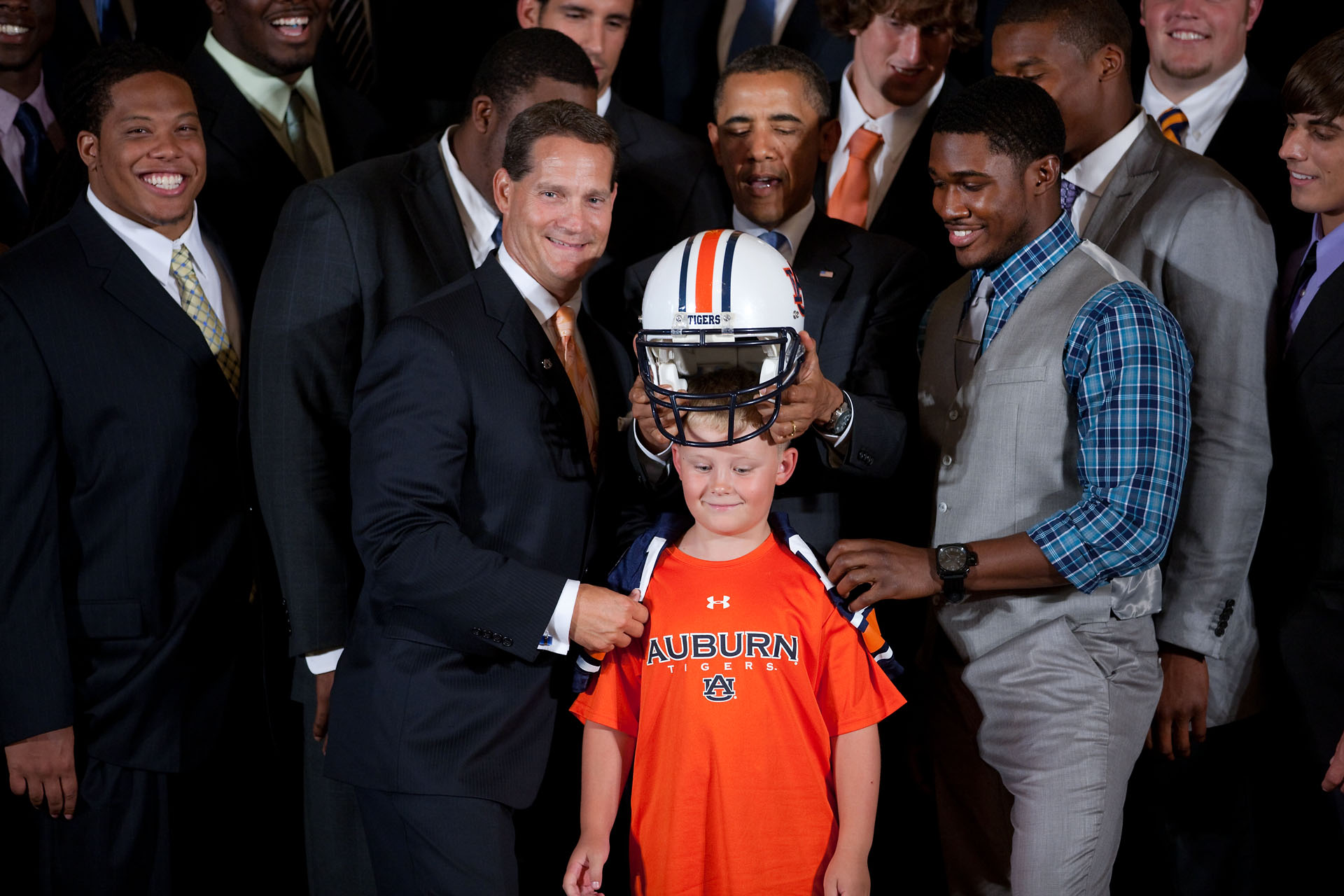 President Barack Obama places an Auburn University football helmet on the head of Ethan Gibbs
