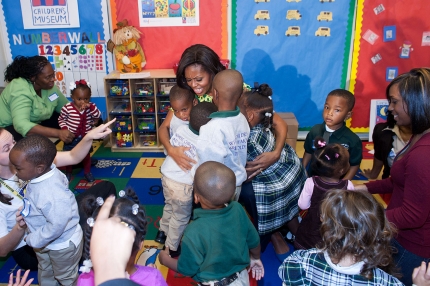 First Lady Michelle Obama shares a group hug with children at Royal Castle Child Development Center