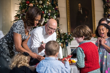 First Lady Michelle Obama and children of military families participate in a craft project in the State Dining Room during the White House holiday press preview, Dec. 4, 2013. Executive Pastry Chef Bill Yosses helps children decorate Springerle cookie orn