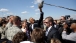 President Barack Obama reaches up to touch a media microphone 