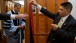 Valet Paul Reyna, right, and Trip Director Marvin Nicholson assist President Barack Obama with his academic regalia 