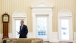 President Obama looks over paperwork between meetings