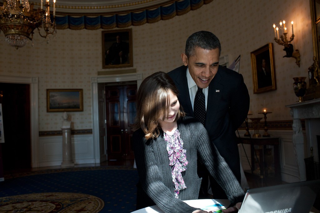 President Obama looks over the shoulder of Hannah Wyman, 11, as she demonstrates her project -- designing and coding a videogame about the environment --  in the Blue Room, Feb. 7, 2012, during the second annual White House Science Fair celebrating student winners of science, technology, engineering, and math (STEM) competitions from across the country (Photo by Pete Souza)